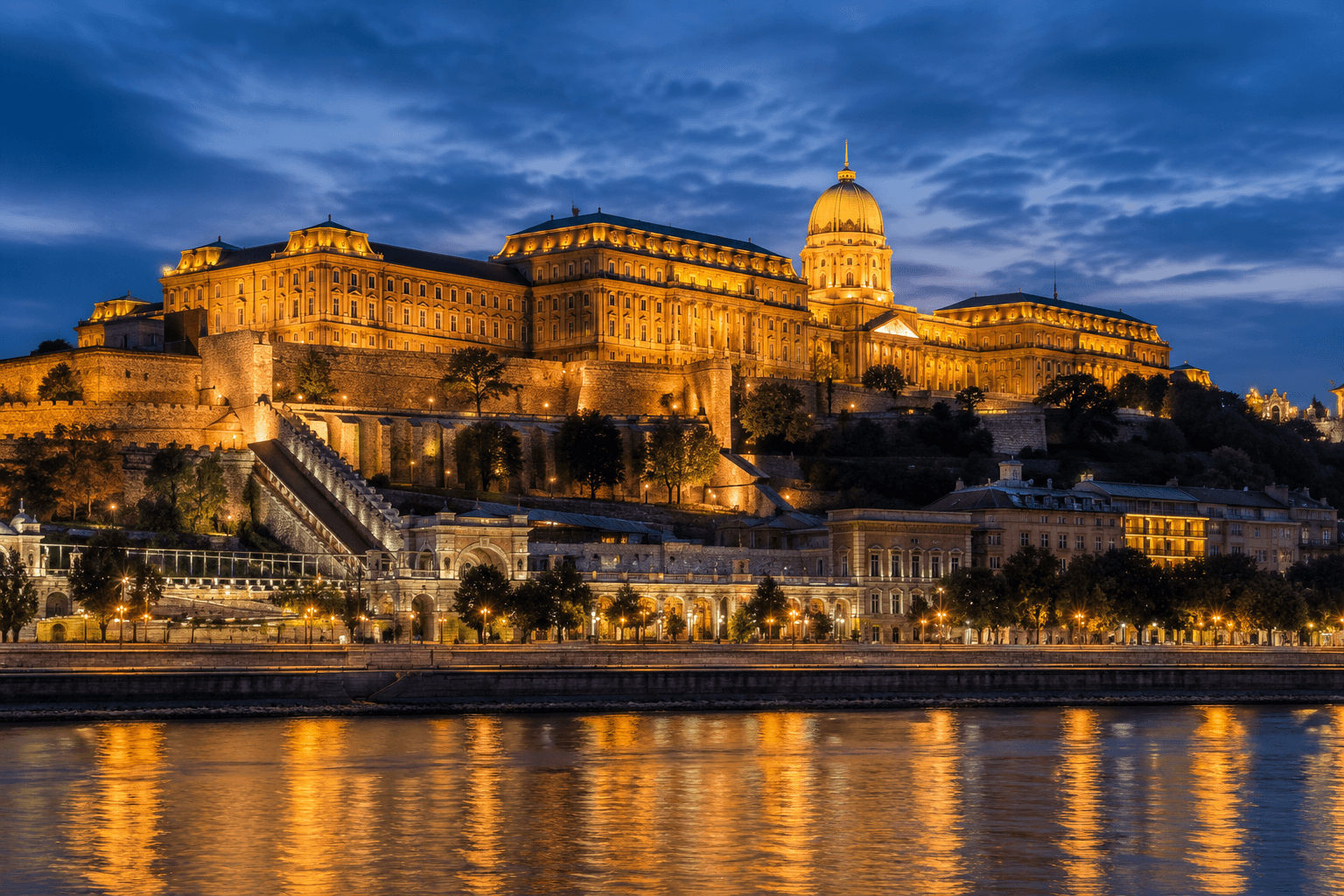 Buda Castle in Budapest illuminated at night above the Danube River with the historic Royal Palace and Castle Hill.