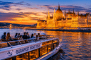 Budapest boat tour on the Danube at sunset with the illuminated Hungarian Parliament Building and Chain Bridge in the background.